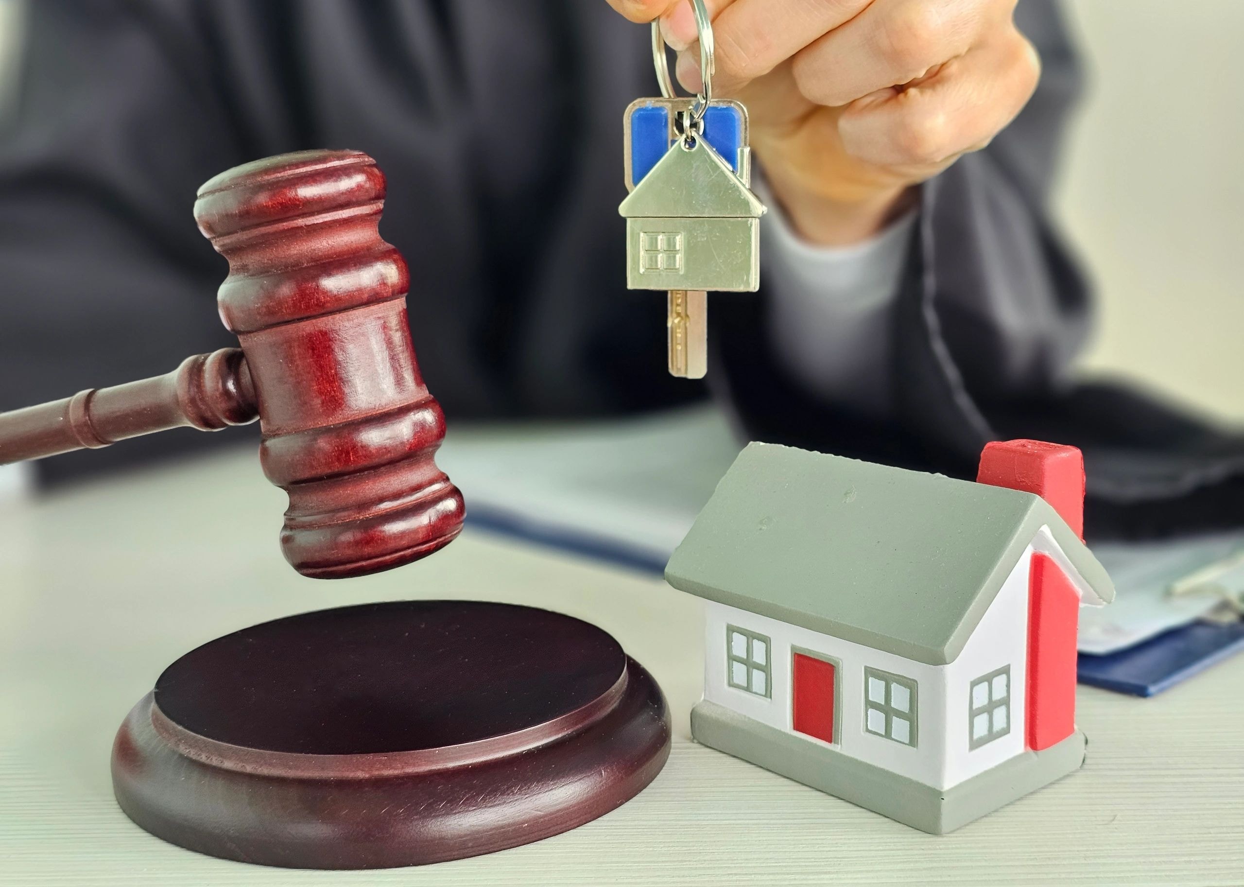 Real estate professional holding house keychain and gavel
